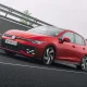 Red Volkswagen Golf GTI side view on road